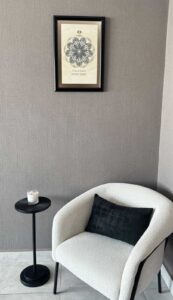 Geometría personal en tinta enmarcada colocada en pared de espacio interior junto a sillón y mesa lateral con decoración minimalista